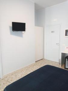 Dieses weiße Zimmer verfügt über einen Flachbild-TV an der Wand. in der Unterkunft Michelangelo Rooms in Catania