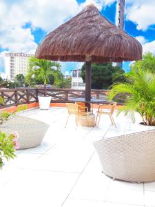 a patio with chairs and a straw umbrella at Pousada Solar Ponta Negra in Natal