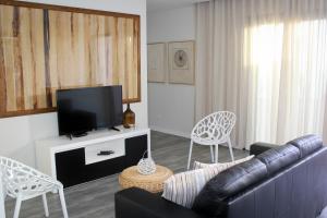 uma sala de estar com um sofá e uma televisão de ecrã plano em Casa das Andorinhas em Estreito da Calheta
