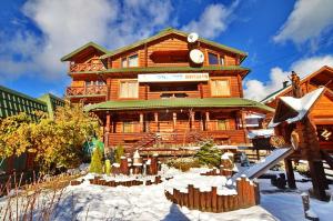 duży drewniany dom z śniegiem przed nim w obiekcie Urochyshe Vyshnya w mieście Bukowel