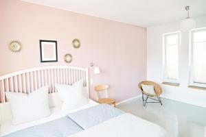 een witte slaapkamer met een bed en een stoel bij ElbQuartier Apartments Magdeburg 'Die Stadtoase' in Maagdenburg