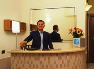 a man in a suit sitting at a reception desk at Hotel Moscatello in Rome