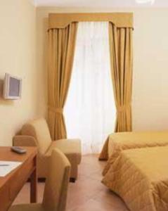 a bedroom with a bed and a desk and a window at Hotel Moscatello in Rome