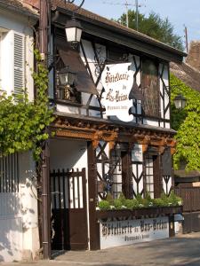 a black and white building with a sign on it at Hôtellerie Du Bas-Bréau in Barbizon