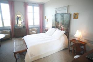 オンフルールにあるChambres d'hotes Autour de la Roseの白いベッドと壁に絵画が飾られたベッドルーム1室