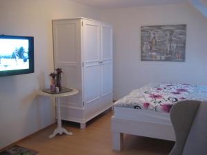 a bedroom with a bed and a cabinet and a television at Ferienhaus Wattenhus in Büsum