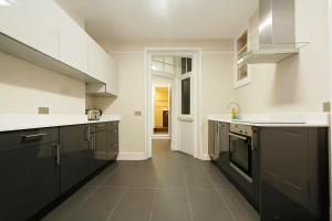 a kitchen with black cabinets and white counter tops at Apartments At Marylebone in London