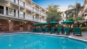 a pool with chairs and umbrellas in front of a hotel at Best Western Plus French Quarter Courtyard Hotel in New Orleans