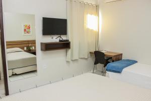 a bedroom with a mirror and a bed and a desk at Hotel São Miguel in Sorriso