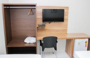 a desk with a television and a chair in a room at Hotel São Miguel in Sorriso