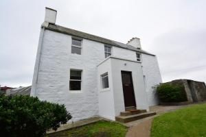 a white house with a black door in a yard at Northness Apartments, Lerwick Self Contained in Lerwick