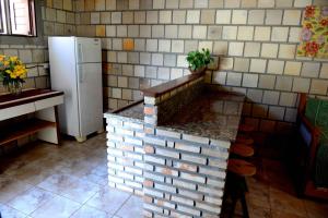 a kitchen with a brick counter and a refrigerator at Recanto do Rei Chalés in São Miguel do Gostoso