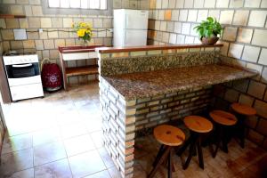 a kitchen with a counter with stools in front of it at Recanto do Rei Chalés in São Miguel do Gostoso