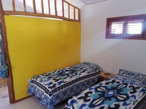 ein Schlafzimmer mit 2 Betten und einer gelben Wand in der Unterkunft A Casa Azul in Barra Grande