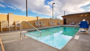 a swimming pool with white chairs and a building at Best Western Plus Lonestar Inn & Suites in Colorado City