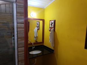 ein Badezimmer mit einem Waschbecken und einer gelben Wand in der Unterkunft A Casa Azul in Barra Grande