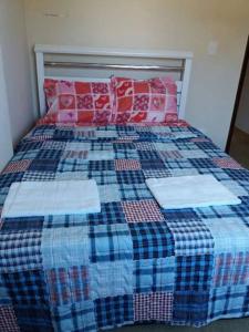 Cama con edredón y almohadas de color azul y rojo en Apartamento Murimar XIII, en Vila Muriqui