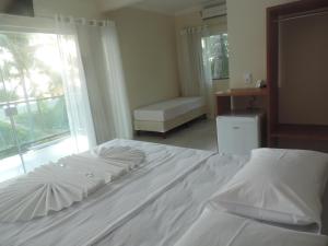 a white bed in a room with a window at Areia do Atlantico Hotel in Porto Seguro