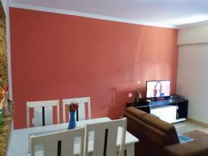 sala de estar con pared roja, sofá y mesa en Apartamento Murimar XIII en Vila Muriqui