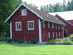 a red barn with white windows on a green field at Björka Storgård B&B in Motala
