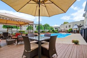 a patio with a table and chairs and an umbrella at Best Western Little River Inn in Simcoe