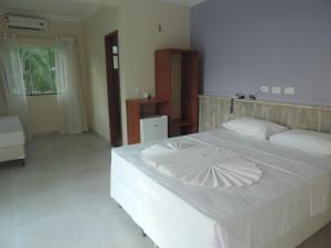 a bedroom with a large white bed with white sheets at Areia do Atlantico Hotel in Porto Seguro