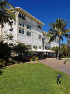 a large white building with palm trees in front of it at Moreton Island Villas and Apartments in Tangalooma