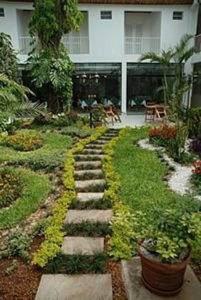 a garden with a stone path in front of a house at Hotel Palmas del Sol in Asunción