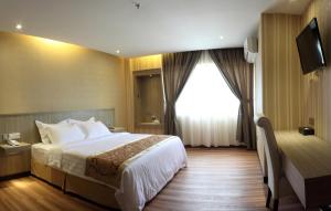 Habitación de hotel con cama y ventana en Mandarin Hotel Kota Kinabalu, en Kota Kinabalu