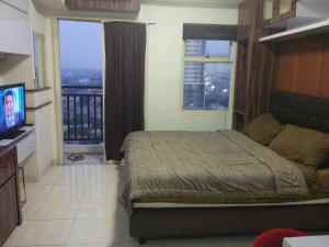 a bedroom with a bed and a tv and windows at DSR Apartment Margonda Residence 2 in Depok