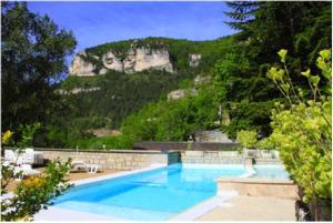 a large swimming pool with a mountain in the background at Hotel de la Jonte in Meyrueis