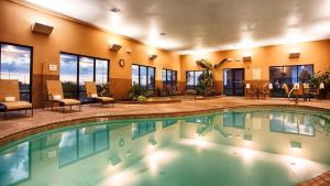 a pool in a hotel with tables and chairs at Best Western Plus Night Watchman Inn & Suites in Greensburg