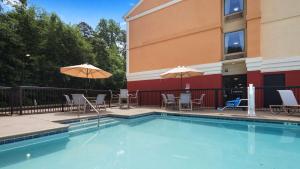 a swimming pool with chairs and umbrellas next to a building at Best Western Plus Huntersville in Huntersville