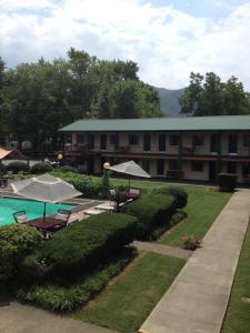 a resort building with a pool and tables and umbrellas at Ridge Top Motel - Bryson City in Bryson City