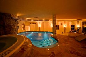 una gran piscina con bañera de hidromasaje y un spa en Landhotel Tharerwirt, en Valdaora