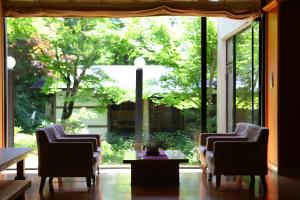 two chairs and a table in a room with a large window at Nukumorino-yado Komanoyu in Kiso