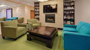 a waiting room with blue chairs and a fireplace at Best Western Garden Inn in Bentleyville