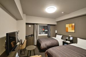 a hotel room with two beds and a flat screen tv at Hotel Route-Inn Yanagawa Ekimae in Yanagawa