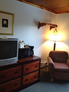a living room with a tv and a chair and a lamp at Ridge Top Motel - Bryson City in Bryson City