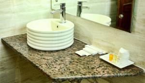 a bathroom counter with a sink and a mirror at Chimbalhar Heights in Pālampur