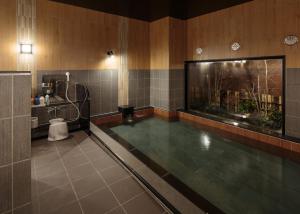 einen Pool in einem Bad mit einem Aquarium in der Unterkunft Hotel Route-Inn Takaoka Ekimae in Takaoka