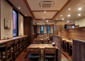 a restaurant with wooden tables and chairs and windows at Hotel Route-Inn Takaoka Ekimae in Takaoka