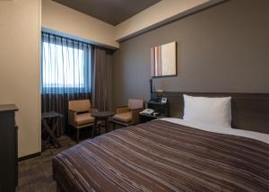 Hotel Route Inn Grand Kitami Ekimae في كيتامي: غرفة فندقية بسرير وطاولة وكراسي