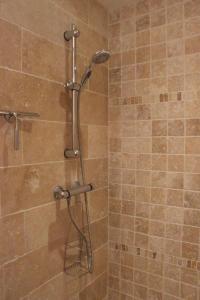 a shower with a shower head in a bathroom at Chambres Aux Bonnes Herbes in Bais