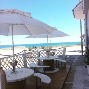 two tables and chairs with an umbrella on the beach at Dimore di Mare in San Pietro Vernotico
