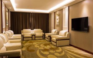 a waiting room with white chairs and a flat screen tv at GreenTree Eastern GuangDong FoShan ShunDe District Huicong City Hotel in Shunde