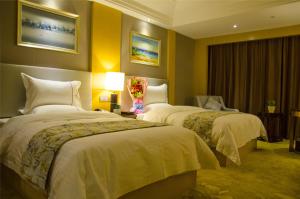 two beds in a hotel room with yellow walls at GreenTree Eastern GuangDong FoShan ShunDe District Huicong City Hotel in Shunde