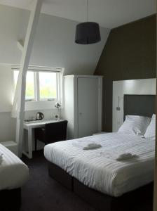 a bedroom with two beds and a desk and a window at Hotel Vossius Vondelpark in Amsterdam