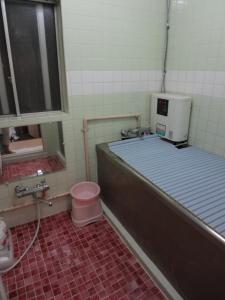 a bathroom with a bed and a toilet in it at Ryokan Torijun in Ota