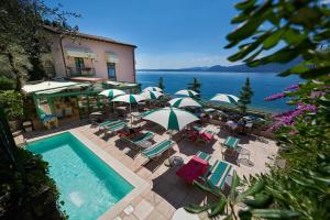 a swimming pool with chairs and umbrellas and a building at Hotel Villa Carlotta in Torri del Benaco